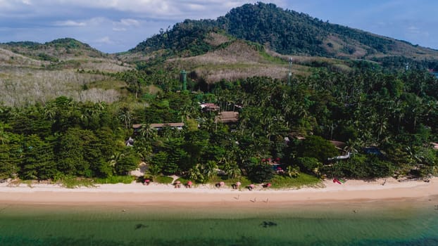 A beautiful view of a calm beach with crystal clear water on the blue sky at Koh Libong, Trang province, Thailand, Andaman Sea with mountains on the beackground