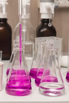 Flasks with liquid colored pink. Chemical analysis, organic test of water in the laboratory