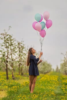 girl with balloons in a young blooming garden