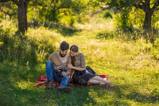 young couple relaxing in nature and looking at photos on a camera