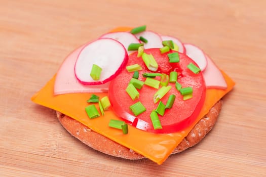 Crispy Cracker Sandwich with Tomato, Sausage, Cheese, Green Onions and Radish on Cutting Board. Easy Breakfast. Quick and Healthy Sandwiches. Crispbread with Tasty Filling. Healthy Dietary Snack