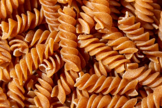 Uncooked Whole Grain Fusilli Pasta: A Culinary Canvas of Whole Wheat Spirals, Creating a Lively and Textured Background for Gourmet Cooking. Whole Grain Twisted Dry Pasta. Whole Wheat Raw Macaroni