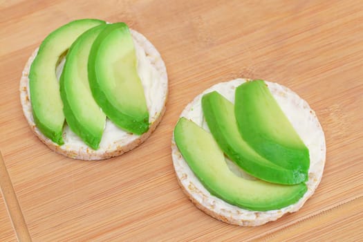 Rice Cake Sandwiches with Fresh Avocado and Cream Cheese on Bamboo Cutting Board. Easy Breakfast. Diet Food. Quick and Healthy Sandwiches. Crispbread with Tasty Filling. Healthy Dietary Snack