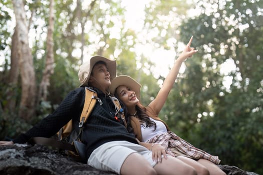 Lovely couple lesbian woman with backpack relaxing while hiking in nature. Loving LGBT romantic moment in mountains.