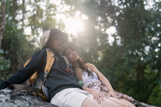 Lovely couple lesbian woman with backpack relaxing while hiking in nature. Loving LGBT romantic moment in mountains.