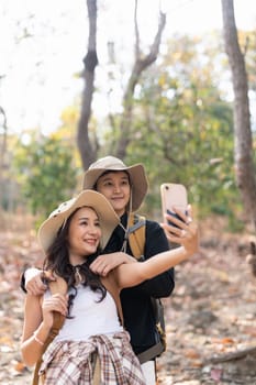 Lovely couple lesbian woman with backpack take a selfie while hiking in nature. Loving LGBT romantic moment in mountains.
