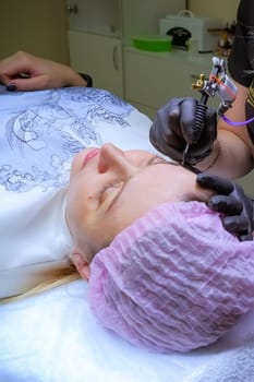 Cosmetologist applying permanent makeup on eyebrows Selective focus and shallow Depth of field