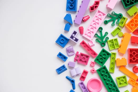 Multicolored plastic building blocks of the designer. Background of plastic colored details building blocks. Parts of bright small spare parts for toys. Close up.