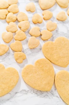 Decorating heart-shaped sugar cookies with pink and white royal icing for Valentine's Day.