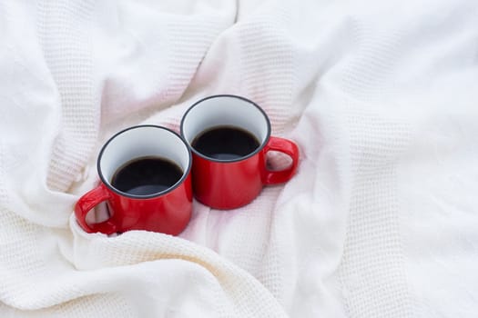 Two cups of coffee in a red heart, standing on a white plaid. Drinking coffee together on Valentine's Day