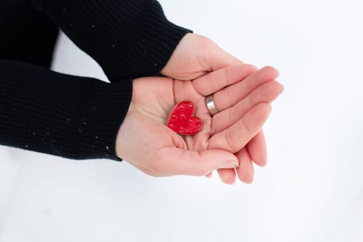 Red heart in the hands of a girl on a light background