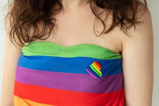 Close-up of a girl wearing a rainbow tube top with a small rainbow ribbon attached to the fabric. LGBT support