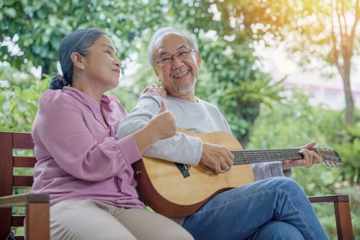 Happy two Asian senior couple elderly man playing the guitar while his wife is singing together at home outdoors, Enjoying lifestyle during retirement life having fun, Activity family health care