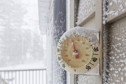 Snow Capped Thermometer Mounted on Wooden House Siding with Freezing Temperature. High quality photo