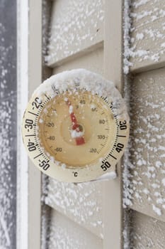 Snow Capped Thermometer Mounted on Wooden House Siding with Freezing Temperature. High quality photo