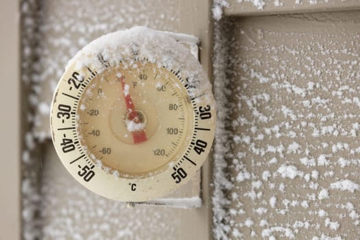 Snow Capped Thermometer Mounted on Wooden House Siding with Freezing Temperature. High quality photo