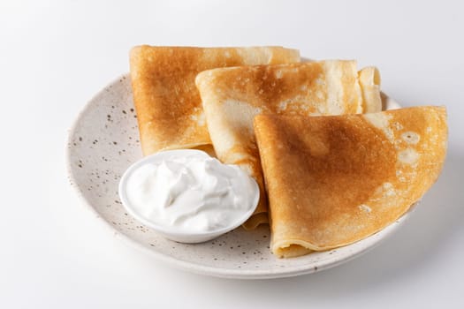 Stack of russian thin pancakes blini with fresh sour cream.
