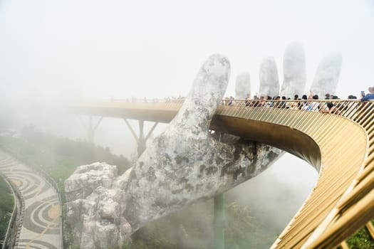 Danang, Vietnam - June 27, 2023: The Golden Bridge is lifted by two giant hands in the tourist resort on Ba Na Hill in Danang, Vietnam.