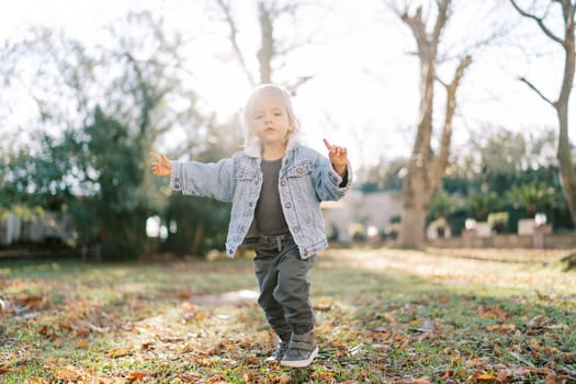 Little girl walks in the park with her index finger up. High quality photo