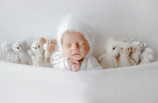 Baby Girl Sleeps Under Blanket With Toys During Newborn Photo Session In Studio