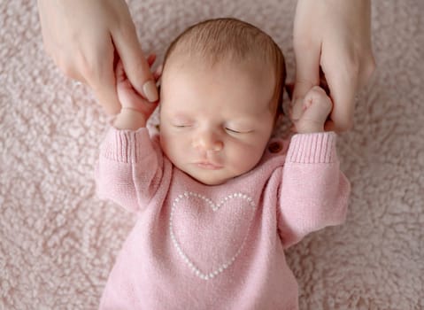Baby Girl In Pink Outfit Sleeps While Mom Holds Her During Newborn Photo Session In Studio