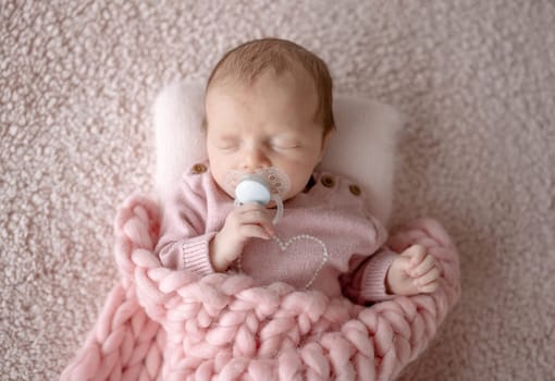 Baby Girl In Pink Outfit Sleeps With Pacifier During Newborn Photo Session In Studio