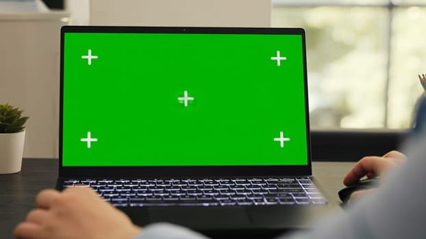 Female manager works on laptop running isolated greenscreen template, checking pc with blank mockup display. Young adult working on startup tasks using chromakey copyspace layout.