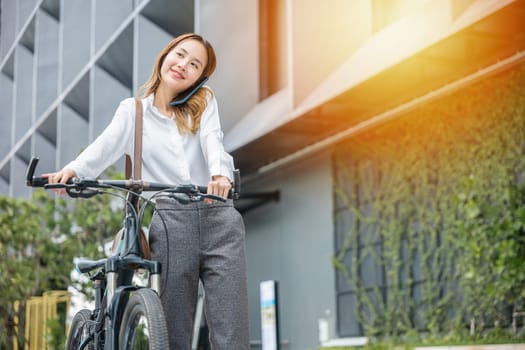A businesswoman with her bike using a smartphone showcases the modern balance of work joy and technology. Her cheerful expression reflects the freedom to stay connected outdoors.