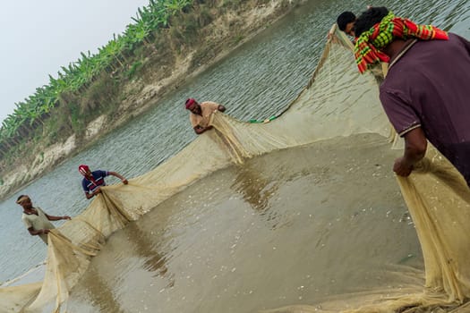 31.12.2023: Bangladesh - Small group of people fishing in river with net