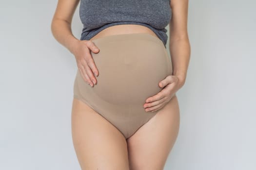 Pregnant bliss: Mom-to-be embraces her baby bump with a soft fabric bandage, providing gentle support. Maternity made comfortable.