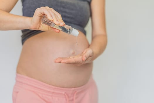 Expectant mom ensures safety, applying gel sanitizer for a clean and healthy pregnancy.