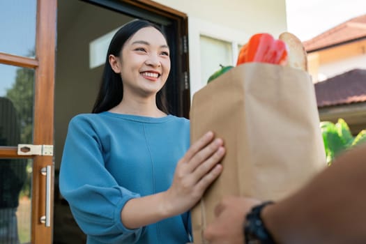 Asian young delivery man delivering package to female customer at home.