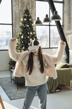 A Christmas tree setting: a lovely young girl wearing a virtual reality headset. High quality photo