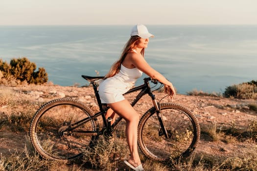 A woman cyclist on a mountain bike looking at the landscape sea. Adventure travel on bike