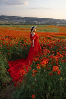 Woman poppy field red dress hat. Happy woman in a long red dress in a beautiful large poppy field. Blond stands with her back posing on a large field of red poppies