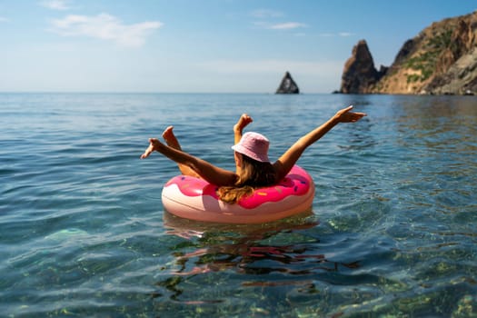 Summer vacation woman in hat floats on an inflatable donut mattress. Happy woman relaxing and enjoying family summer travel holidays travel on the sea