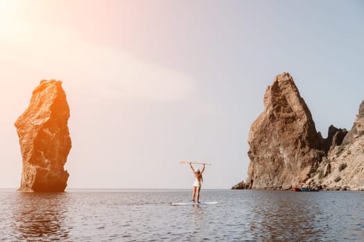 Close up shot of beautiful young caucasian woman with black hair and freckles looking at camera and smiling. Cute woman portrait in a pink bikini posing on a volcanic rock high above the sea