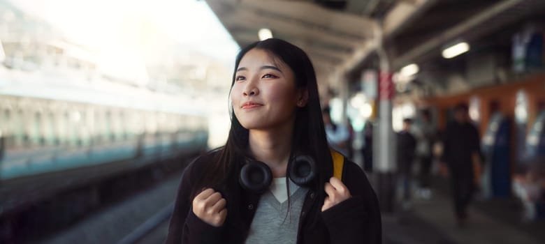 Asian, woman at train station for travel, commute or holiday with smile on face and freedom outdoor. Railway, walking on platform and transportation, journey for adventure in China with happiness.