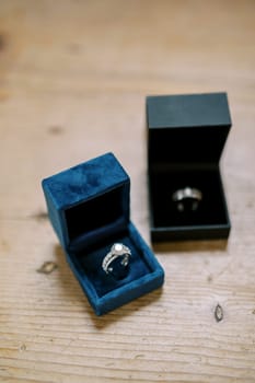 Wedding rings lie in boxes on a wooden table. High quality photo