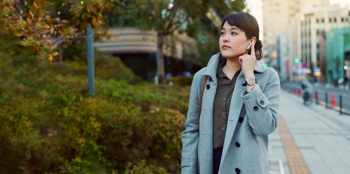 Woman, Asian and walk on sidewalk, travel or commute to work with professional in city with earphones. Listening to music on journey, podcast and commuter on urban street in Tokyo with playlist.