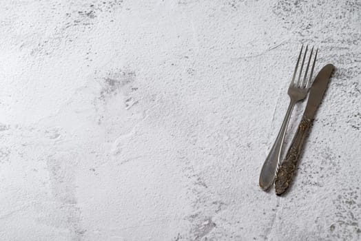 Antique fork and knife on white stone table