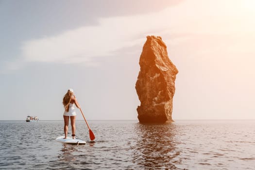 Close up shot of beautiful young caucasian woman with black hair and freckles looking at camera and smiling. Cute woman portrait in a pink bikini posing on a volcanic rock high above the sea