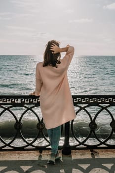 Woman travel sea. Young Happy woman in a long red dress posing on a beach near the sea on background of volcanic rocks, like in Iceland, sharing travel adventure journey