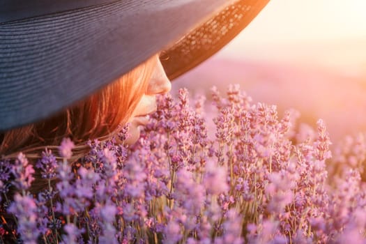 Close up portrait of young beautiful woman in a white dress and a hat is walking in the lavender field and smelling lavender bouquet.