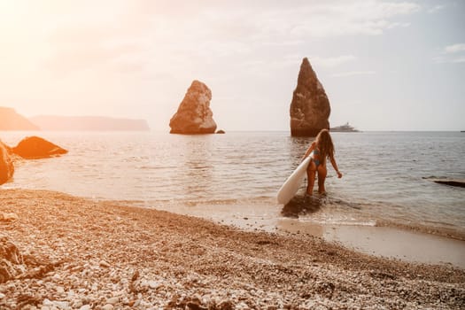 Close up shot of beautiful young caucasian woman with black hair and freckles looking at camera and smiling. Cute woman portrait in a pink bikini posing on a volcanic rock high above the sea