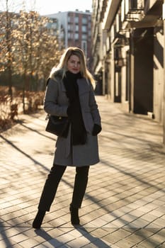 Young stylish hipster girl wearing modern trench coat walking in urban city smiling happy. Caucasian female model. Fall fashion. High quality photo