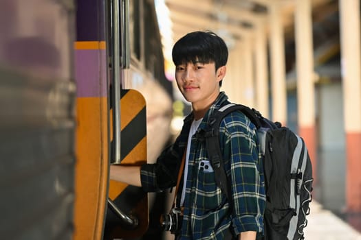 Handsome male traveler with a backpack getting on the train. Travel and vacations concept.