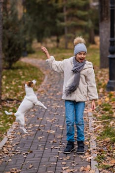 Caucasian girl playing with a dog for a walk in the autumn park