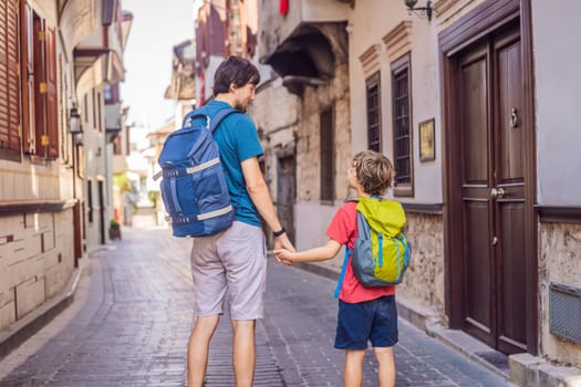 Happy father and son tourists on background of old street of Antalya. Traveling with kids concept. male tourist traveler discover interesting places and popular attractions and walks in the old city Kalechi of Antalya, Turkey. Turkiye.