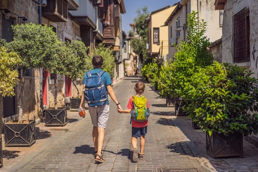 Happy father and son tourists on background of old street of Antalya. Traveling with kids concept. male tourist traveler discover interesting places and popular attractions and walks in the old city Kalechi of Antalya, Turkey. Turkiye.